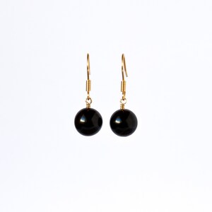 May include: A pair of gold dangle earrings with black round beads.