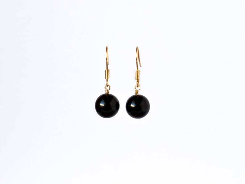 May include: A pair of gold dangle earrings with black round beads.
