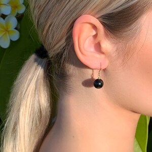 May include: A pair of gold earrings with black round gemstone drops.