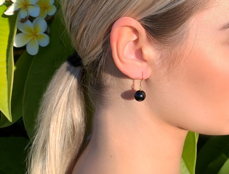 May include: A pair of gold earrings with black round gemstone drops.