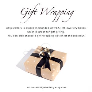 May include: A brown gift box with white stars and a black ribbon. The text "Gift Wrapping" is at the top of the image. The text "All jewellery is placed in branded AIR+EARTH jewellery boxes, which is great for gift giving. You can also choose a gift wrapping option at the checkout." is below the image. The text "airandearthjewellery.etsy.com" is at the bottom of the image.