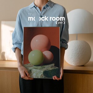 Könnte beinhalten: Ein gerahmter Kunstdruck mit drei Kugeln in Rosa und Grün, die auf einem strukturierten grünen Stein vor rotem Hintergrund liegen. Der Druck wird von einer Person gehalten. Der Text "the mock room (psd)" ist sichtbar.