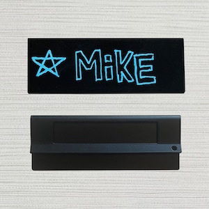 May include: A black name tag with a white star and the name "MIKE" written in blue.