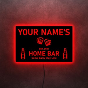 May include: Red neon sign with black background that reads "YOUR NAME'S EST. 2020 HOME BAR Come Early Stay Late" with beer bottle and mug icons.