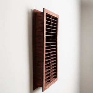 May include: A rectangular wall-mounted wooden storage organizer featuring a dark brown finish and a grid of multiple horizontal shelves. The unit has a deep frame with visible side panel construction and is oriented vertically for display.