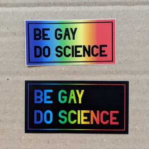 May include: Two rainbow-colored stickers with the text "Be Gay Do Science" in black lettering. The stickers have a black border.