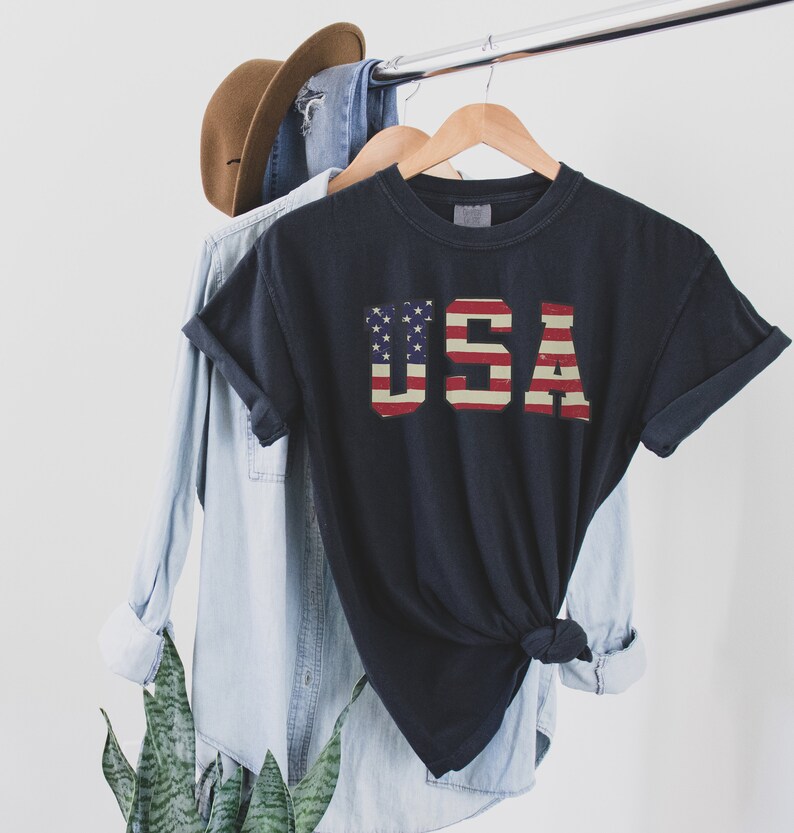 May include: A black t-shirt with a vintage-style American flag graphic that spells out "USA".