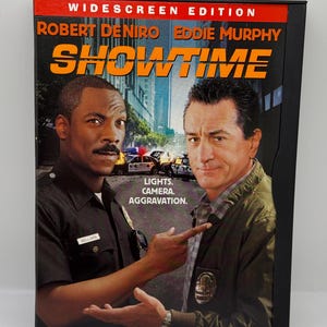 May include: DVD case for the movie Showtime, featuring Robert De Niro and Eddie Murphy on the cover. The text "Lights. Camera. Aggravation." is printed on the cover.