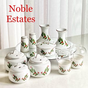 Puede incluir: Un juego de candelabros, saleros y pimenteros y tarros decorativos de cerámica blanca con temática navideña con un diseño de acebo y bayas. El juego está hecho por Noble Estates.