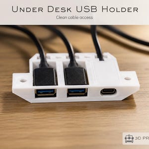 May include: A white 3D printed under desk USB holder featuring two USB-A ports and one USB-C port. The device is shown with two black cables plugged into the USB-A ports. The text "UNDER DESK USB HOLDER" and "3D PRINTED" appear in the image.