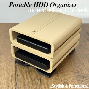 May include: A beige portable HDD organiser with two stacked compartments, each holding a black hard drive. The text "Portable HDD Organiser" and "Underdesk or On Desk" is visible. The organiser is on a wooden surface. The text "Stylish & Functional" is also visible.