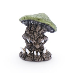 May include: A small, brown, and green figurine of a mushroom with a face. The mushroom has a green cap and a brown, gnarled stem with a face. The face has two eyes, a nose, and a mouth with teeth.