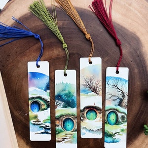 May include: Four watercolor bookmarks featuring a whimsical illustration of a hobbit hole with a green door. Each bookmark has a different colored tassel: blue, green, orange, and red.