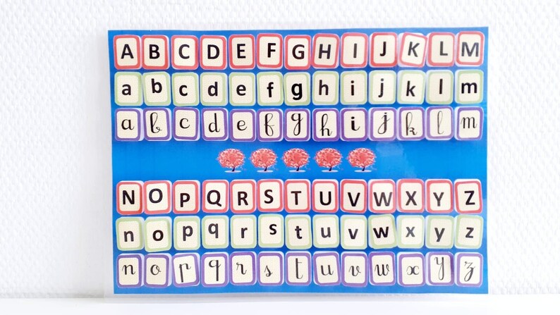 May include: A blue and white alphabet chart with three red trees. The chart has three rows of letters, with the first row in uppercase, the second row in lowercase, and the third row in cursive lowercase.