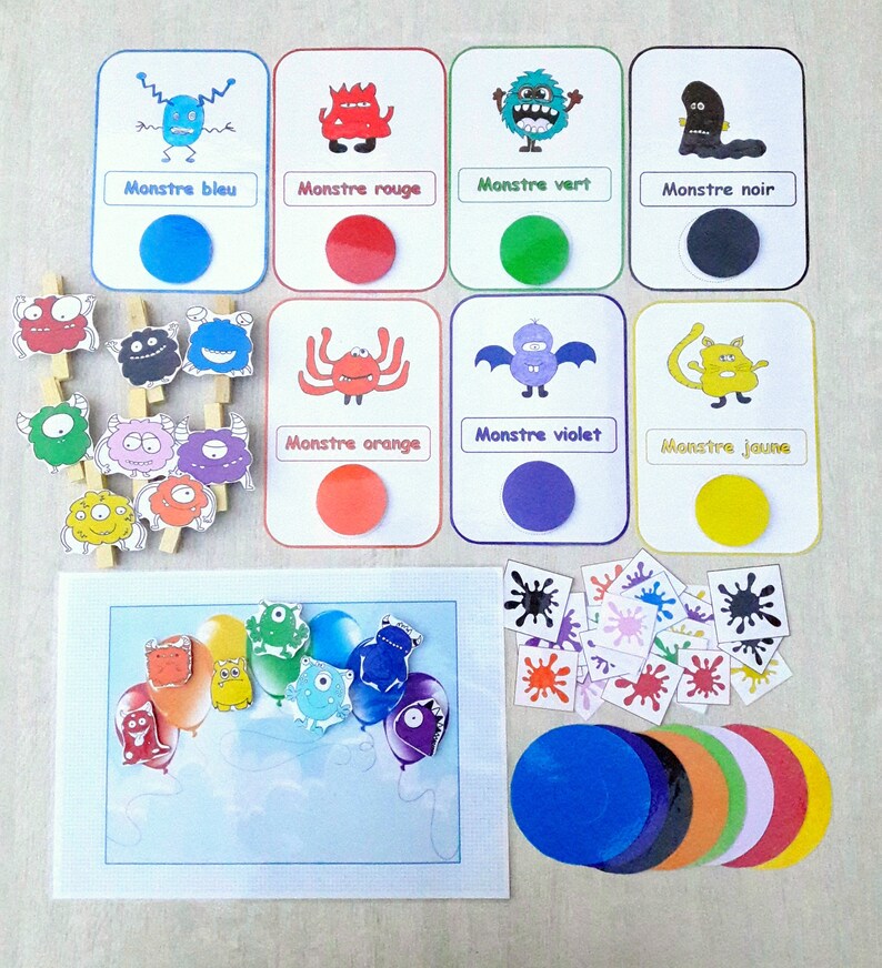 May include: A set of colorful monster-themed educational cards with matching color circles. The cards feature different monsters in various colors, including blue, red, green, black, orange, violet, and yellow. The set also includes a game board with a rainbow of balloons and matching color circles.