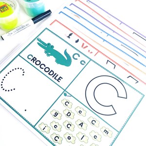 May include: A green crocodile illustration with the word "CROCODILE" printed below it. A dotted line outlines the letter "C" and a larger, solid outline of the letter "C" is shown. The letter "C" is repeated in a cloud-shaped pattern with other letters.