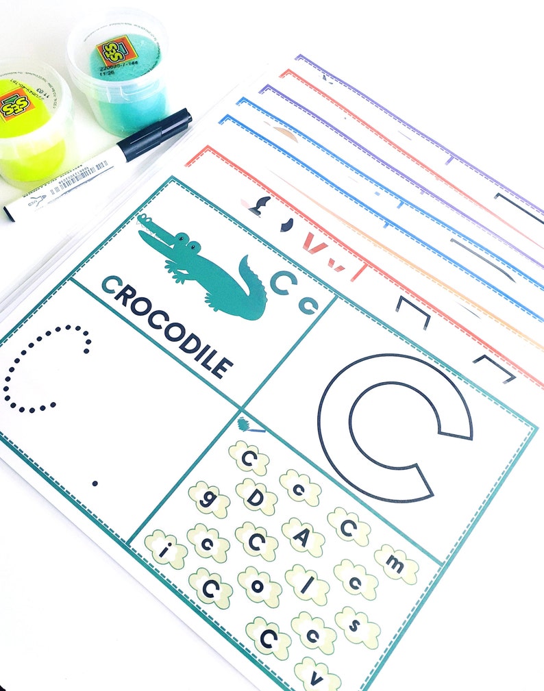 May include: A green crocodile illustration with the word "CROCODILE" printed below it. A dotted line outlines the letter "C" and a larger, solid outline of the letter "C" is shown. The letter "C" is repeated in a cloud-shaped pattern with other letters.