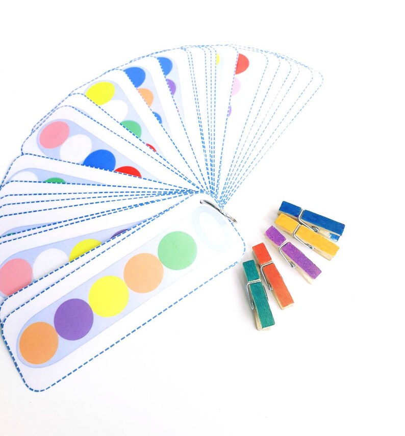 Puede incluir: Un conjunto de tarjetas coloridas con c&iacute;rculos en ellas, dispuestas en forma de abanico. Las tarjetas se utilizan para una actividad de coincidencia de colores. Tambi&eacute;n hay pinzas para la ropa de colores.