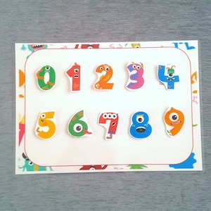 May include: A white card with a red border features colorful monster-shaped numbers from 1 to 9. Each number has a different color and a unique monster face.