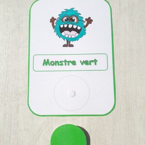 May include: A green monster with a toothy grin and glasses is on a white card with the text "Monstre vert". A green circle is below the card.