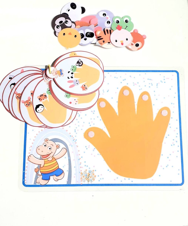 May include: A colorful learning game with a hand-shaped board and animal-themed cards. The board has a yellow hand with five fingers and a blue border. The cards feature different animals, including a panda, a raccoon, a tiger, a chicken, and a squirrel. The cards are arranged in a circle around the hand.