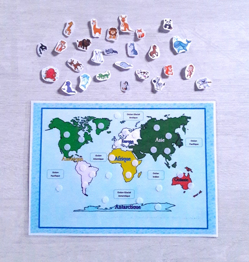 May include: A world map with continents labeled in French, including "Amerique", "Afrique", "Europe", "Asie", and "Antarctique".  The map has white dots on each continent, and there are small animal stickers around the map.