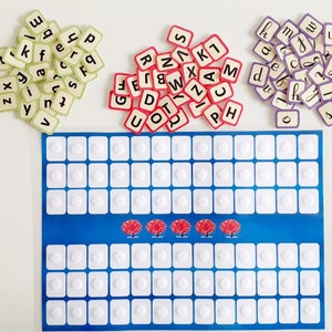 May include: A blue game board with white circles and three red trees. There are three piles of letter tiles in different colours: green, red, and purple.