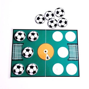 May include: A green and white soccer game board with a yellow center circle and a score of 5. There are six white circles on the board and six black and white soccer balls. There are six additional black and white soccer balls on a white background.