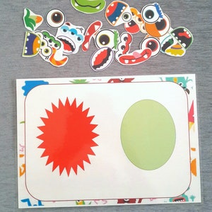 May include: A white card with a red star and a green circle on it. The card is surrounded by a border of colorful monster faces.