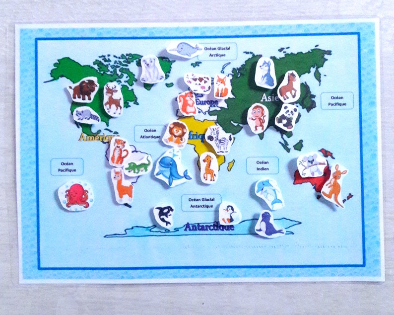 May include: A colorful world map with animal stickers representing different continents. The map includes the names of the continents and oceans in French. The animals include a giraffe, zebra, tiger, lion, kangaroo, penguin, polar bear, octopus, dolphin, and more.