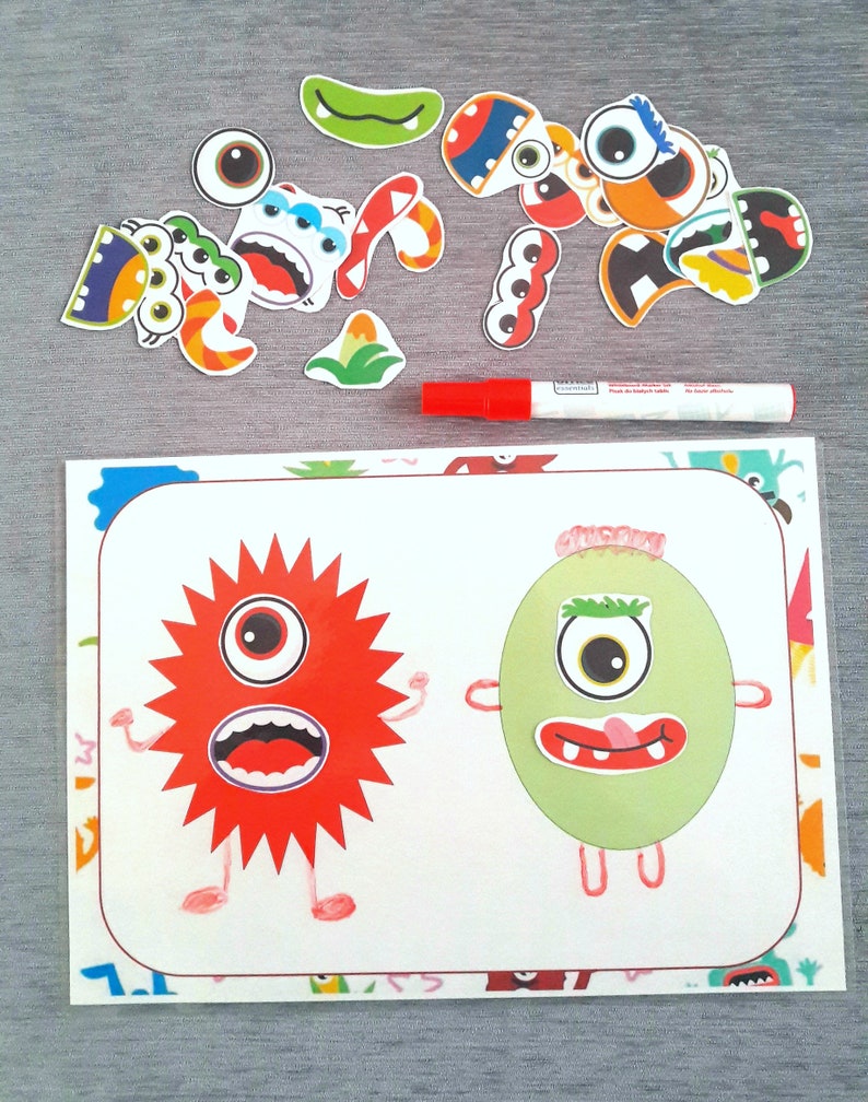 May include: A white card with two monster illustrations. The monster on the left is red with a star shape and the monster on the right is green and oval shaped. Both monsters have eyes, mouths, and arms. There are colorful monster stickers around the card.