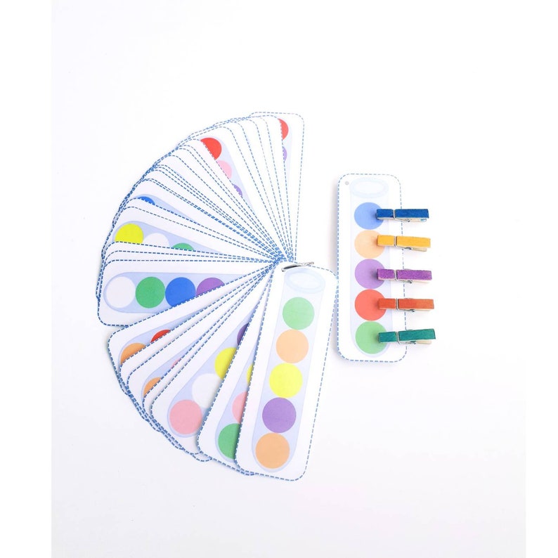 Puede incluir: Un conjunto de tarjetas circulares de colores con pinzas para la ropa a juego. Las tarjetas est&aacute;n dispuestas en forma de abanico y las pinzas para la ropa est&aacute;n alineadas verticalmente. Los colores de los c&iacute;rculos y las pinzas para la ropa son rojo, naranja, amarillo, verde, azul, morado y blanco.