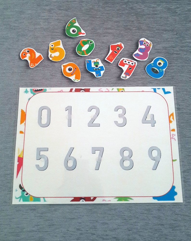 May include: A white board with the numbers 0-9 printed in gray. There are ten colorful monster-shaped pieces with numbers 0-9 printed on them.