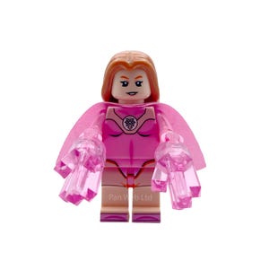 May include: A pink Lego superhero figure with a light pink cape and translucent pink hand accessories. The figure has a light skin tone, red hair, and a pink costume with a circular emblem on the chest.