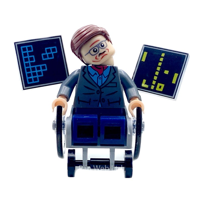 May include: A Lego minifigure of a man in a wheelchair, wearing glasses, a suit, and a red tie. Two black and blue game screens are behind the figure. The figure has brown hair and a serious expression.