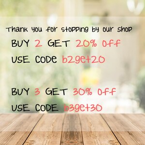 May include: A sign with a blurred background of green foliage. The sign says "Thank you for stopping by our shop. BUY 2 GET 20% Off USE CODE b2ge+20 BUY 3 GET 30% Off USE CODE b39e+30"