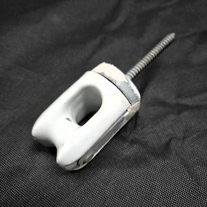 May include: A white ceramic electrical insulator featuring a central opening and a metal screw-in mounting bolt. The component has a smooth, glossy finish on the ceramic portion and a weathered, metallic texture on the base and threaded bolt.