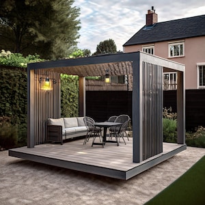 May include: A modern outdoor patio structure with a gray wooden deck, a sofa, and a table with chairs. The structure has a dark gray frame and vertical wooden slats. Two hanging lights illuminate the space, set against a backdrop of greenery and a house.