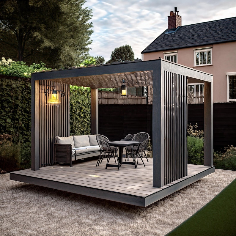 May include: A modern outdoor patio structure with a gray wooden deck, a sofa, and a table with chairs. The structure has a dark gray frame and vertical wooden slats. Two hanging lights illuminate the space, set against a backdrop of greenery and a house.