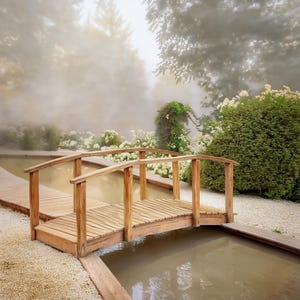 Puede incluir: Un puente de madera con barandilla curva cruza un pequeño estanque en un jardín. El puente es de madera clara y está rodeado de exuberante vegetación, flores blancas y una atmósfera brumosa, evocando serenidad.