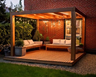 May include: A wooden pergola with string lights and a built-in deck. The pergola is attached to a brick building and has two seating areas with cushions. The deck is made of wood planks and has a light brown finish.