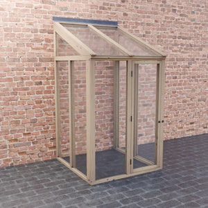 以下が含まれることがあります： ガラスの屋根とドアが付いた木製のフレームの温室。温室はレンガの壁に取り付けられています