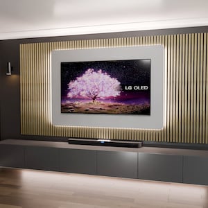 Könnte beinhalten: Ein modernes Wohnzimmer mit einem großen Flachbildfernseher, der an einer Wand mit Holzverkleidung montiert ist. Der Fernseher zeigt eine Naturszene mit einem rosa Baum. Der Fernseher ist von einem weißen Rahmen mit einem dünnen weißen Licht umgeben. Der Fernseher ist über einem dunkelgrauen Unterhaltungszentrum mit einer schwarzen Soundbar montiert. Der Raum hat einen hellbraunen Holzboden.