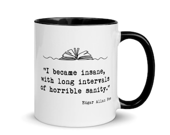 Puede incluir: Taza de cerámica blanca con borde y asa negros. La taza presenta una ilustración en blanco y negro de un libro abierto con la cita "Me volví loco, con largos intervalos de horrible cordura." de Edgar Allan Poe.