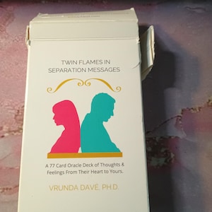May include: A white box with a gold border and the text "Twin Flames in Separation Messages" on the front. The box contains a 77-card oracle deck of thoughts and feelings from their heart to yours. The box is designed by Vrunda Dave, Ph.D.