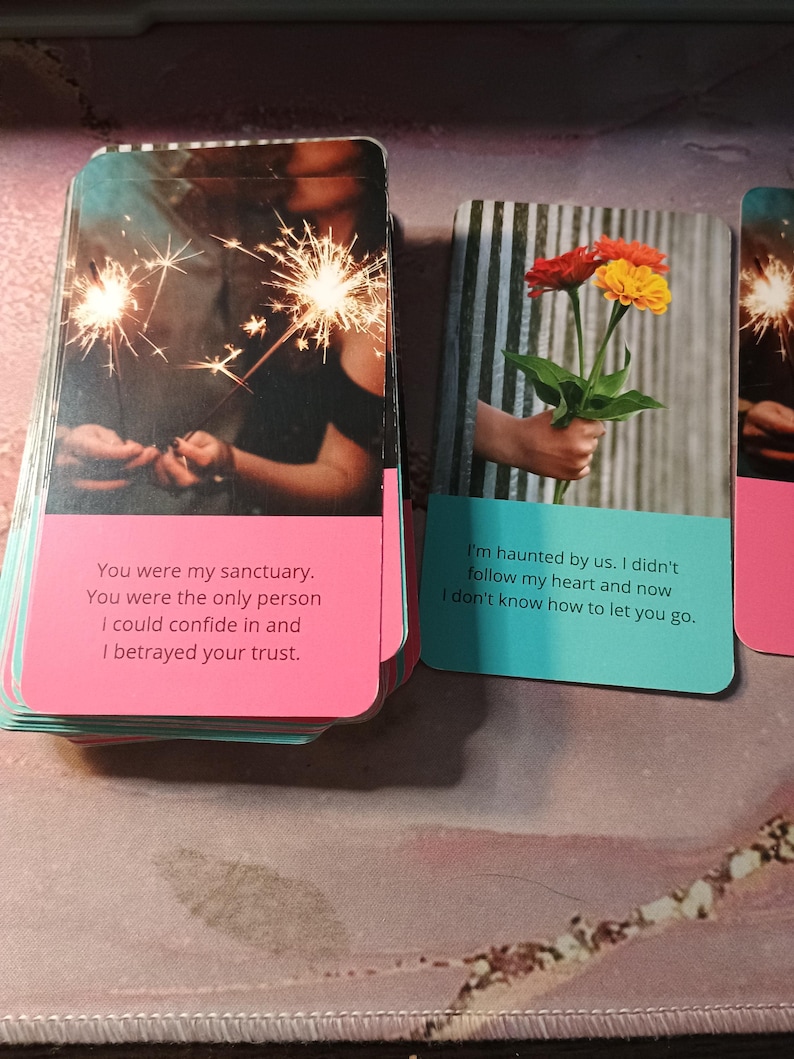 May include: Two cards with pink and blue borders and text. The first card shows a couple holding sparklers and the text "You were my sanctuary. You were the only person I could confide in and I betrayed your trust.". The second card shows a hand holding a bouquet of orange and red flowers and the text "I'm haunted by us. I didn't follow my heart and now I don't know how to let you go."