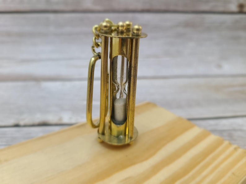 Discover the elegance of time with our Handmade Brass Sand Timer Keychain. Crafted with skillful artistry, this miniature hourglass captures the essence of both functionality and aesthetic appeal.