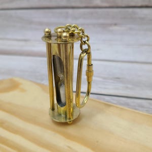 Discover the elegance of time with our Handmade Brass Sand Timer Keychain. Crafted with skillful artistry, this miniature hourglass captures the essence of both functionality and aesthetic appeal.