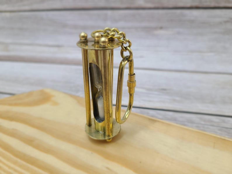 Discover the elegance of time with our Handmade Brass Sand Timer Keychain. Crafted with skillful artistry, this miniature hourglass captures the essence of both functionality and aesthetic appeal.