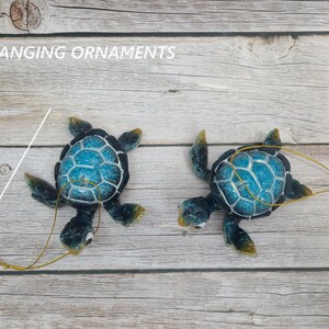 A whimsical blue cartoon turtle ornament, featuring a delightful design with a vibrant blue shell and expressive eyes. The ornament is adorned with playful details, bringing a sense of charm and joy